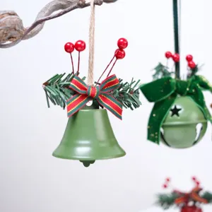 Dettaglio campana di Natale con aghi di pino, bacche rosse e fiocco per decorazioni.