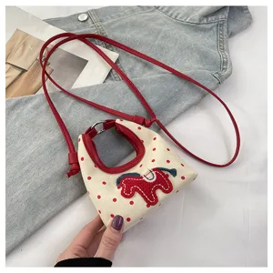 Detalle de un bolso bandolera crema con lunares rojos y un lindo aplique de caballo