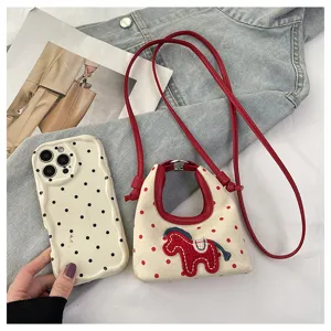Detalle del mini bolso bandolera de lona con bordado de poni rojo y motivo de lunares