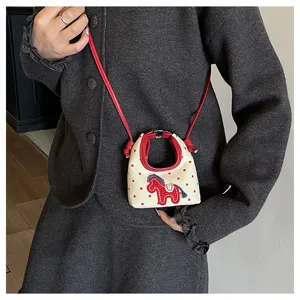 Primer plano del bordado de caballo en un bolso bandolera de lona con lunares rojos