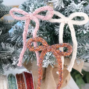 Dettaglio fiocco in filato lavorato a maglia, decorazione albero di Natale e nastro regalo.