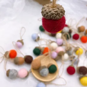Colorful felt acorn Christmas hanging ornaments with natural caps and twine loops for DIY crafts.