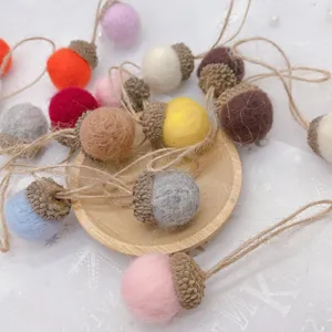 Wool felt acorn ornaments with natural caps and twine, perfect for Christmas DIY decor.