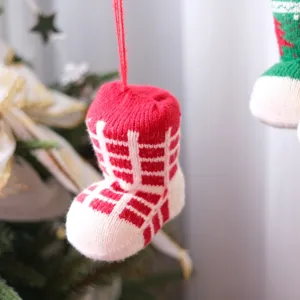 Close-up of a festive red and white knitted Christmas sock ornament hanging on tree.