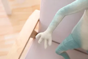 Close-up detail shot of funny alien plush toy arm and hand, soft green fabric, cute doll.