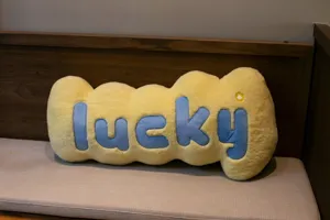 Soft yellow plush lucky letter throw pillow detail shot, cozy home sofa decorative cushion.