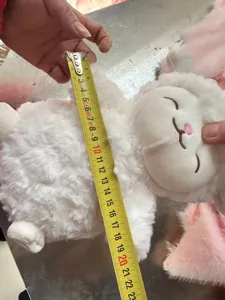Weiszes Plueschtier Puppen Detailansicht zeigt Groessenmessung mit Massband fuer Kinder.