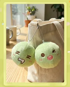 Vista dettagliata del ciondolo in peluche verde, materiale morbido con viso ricamato e design.