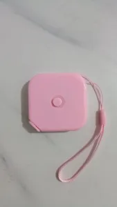 Dettaglio del metro a nastro quadrato rosa retrattile con comodo cordino per uso quotidiano.