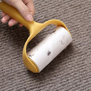 Lint roller with yellow plastic handle and tearable sticky paper for removing pet hair and dust.