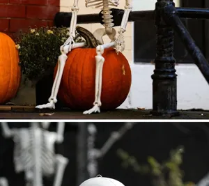 Detailansicht einer lebensgroßen Halloween-Skelettstütze, die auf einem Kürbis sitzt