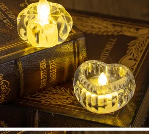 Close-up of transparent heart and pumpkin shaped glass candle holders with warm light
