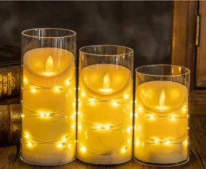 Close-up detail of three LED flameless candles in glass cylinders with warm fairy lights