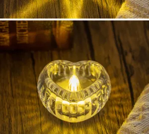 Close-up of a warm glowing heart-shaped transparent glass candle holder on wood