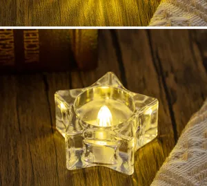 Warm amber glow from an LED tea light inside a star-shaped clear glass candle holder.