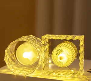 Nahaufnahme von quadratischen und runden Kristall-LED-Kerzen mit warmem Licht