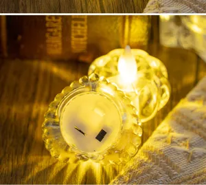 Detail view showing the bottom switch and warm LED light effect of a transparent tea light holder.