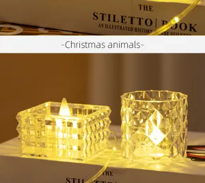 Makro-Detail von Kristallglas-Kerzenhaltern mit warmen LED-Lichtern auf weißen Büchern.