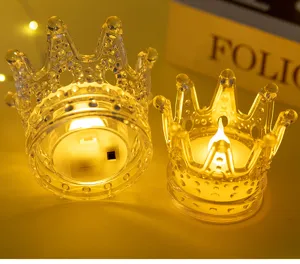 Detail view of two transparent LED crown-shaped candles with warm yellow light.