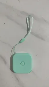 Primo piano di dettaglio del metro a nastro quadrato verde menta con pratico cordino.