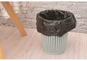 Vista detallada de bolsa de basura de plástico negro instalada en papelera hogareña.