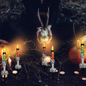 Halloween skeleton hand garden stakes with LED candles in a spooky yard setting
