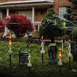 Close-up of Halloween skeleton hand LED candle stakes illuminating a spooky lawn garden