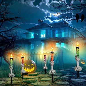 Detail of five skeleton hand candle stakes illuminating a spooky haunted house garden.