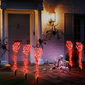 Mani di scheletro di Halloween rosse luminose e oggetti di scena in un cortile spettrale