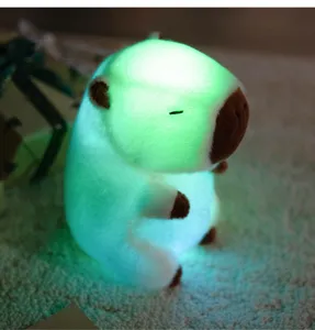 Close-up detail view of the glowing capybara plush toy emitting soft green LED light in the dark.