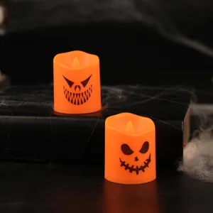 Two orange Halloween LED candles with scary pumpkin faces on dark background