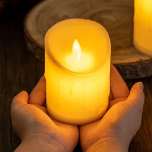 Bougie LED sans flamme avec effet de cire coulante réaliste tenue dans les mains