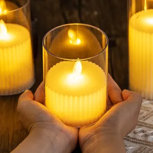 Warm yellow LED flickering flameless candle lamp in clear cylindrical glass container decor