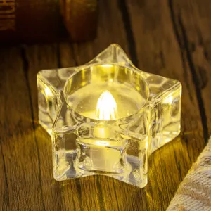 Transparent star shaped LED tea light candle with warm yellow glow on wooden background