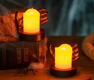A detailed atmospheric close-up of Halloween LED tea lights held by creepy black skeleton hands.
