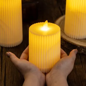 Romantic warm white LED flameless pillar candle with ribbed texture held in hands for scale