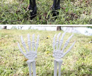 Detailweergave van witte skelethand-tuinstekers in een gazon voor Halloween-decoratie.