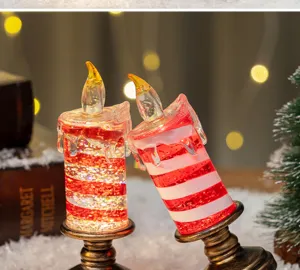 Vista ravvicinata di candele LED festive con glitter rossi e basi in bronzo