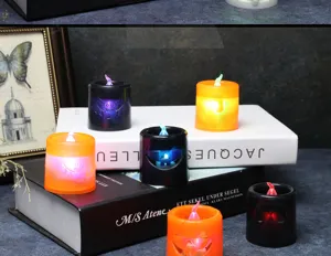 Atmospheric close-up of glowing Halloween LED candles with pumpkin and bat designs