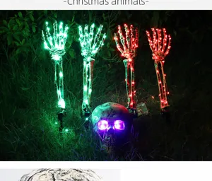 Halloween skeleton hand and skull garden stakes with glowing LED lights in the night