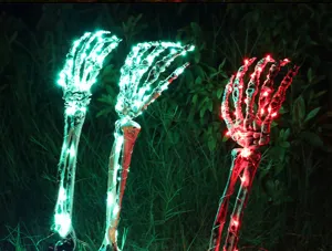 Halloween LED lighted skeleton hands glowing garden stakes in dark grass at night