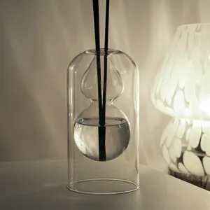 Detalle de difusor de aromas de vidrio transparente, diseño minimalista con varillas negras.