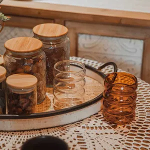 Detailed view of aesthetic ripple glass cups and wooden lid storage jars on a cozy tray.