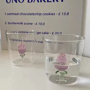 Vista detallada de una taza de vidrio exquisita con rosa rosa 3D dentro, escena de mesa elegante.