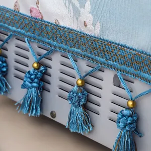 Close-up detail of pastoral fabric microwave cover with elegant blue tassels and woven trim.