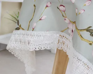Cotton linen tablecloth with floral pattern and white lace trim for dining table decor detail view