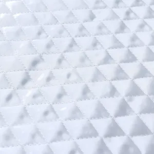 Primer plano detallado del tejido blanco acolchado con patrón de rombos y fina textura de costura.