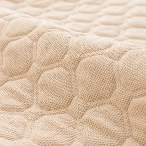Close-up of quilted fabric headboard cover texture, showing soft padded hexagonal details.