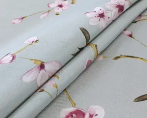 Close-up of light grey cotton linen fabric with elegant pink cherry blossom floral pattern.