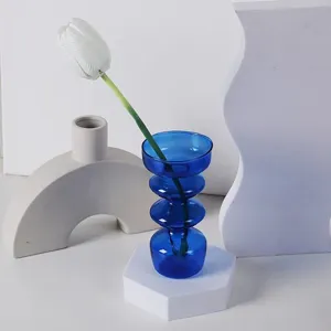 Gros plan sur le détail du vase en verre empilé bleu dans un décor minimaliste moderne.